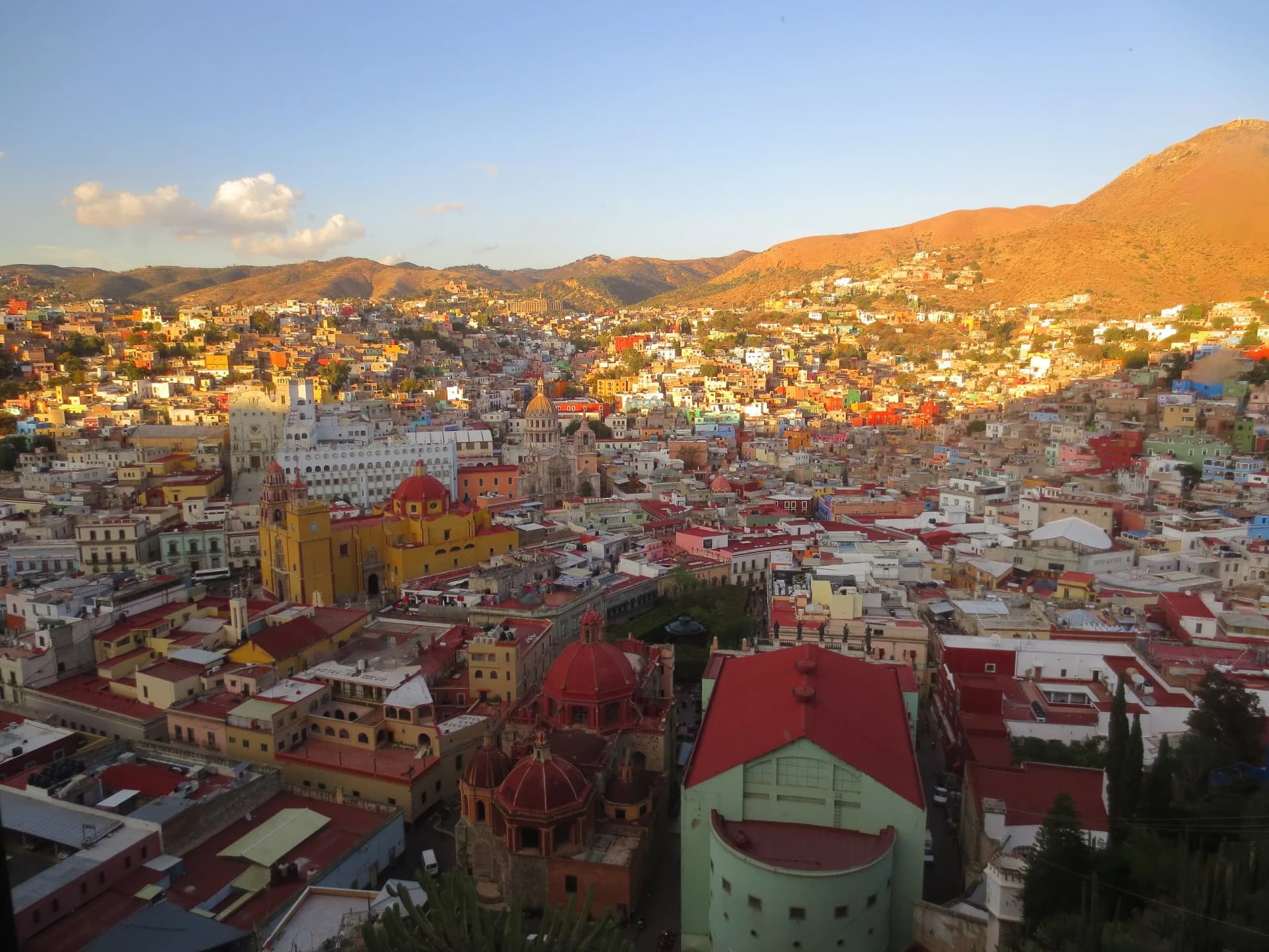 Vista de Guanajuato al atardecer con la Basílica amarilla y casas de colores sobre los cerros